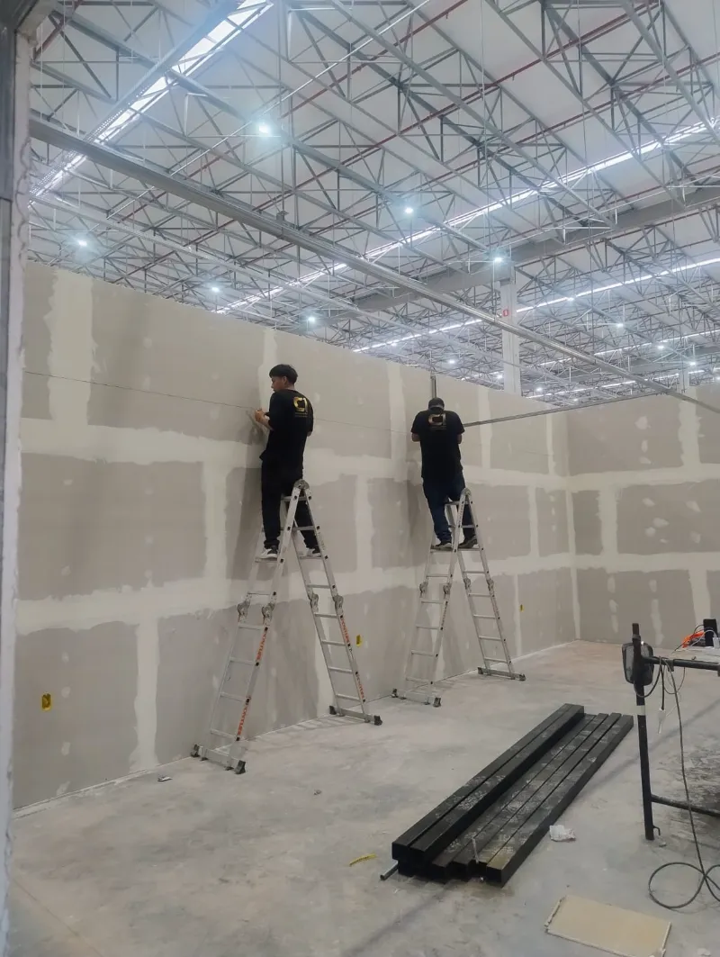 Equipe da C1 tratando juntas de drywall em pé-direito alto